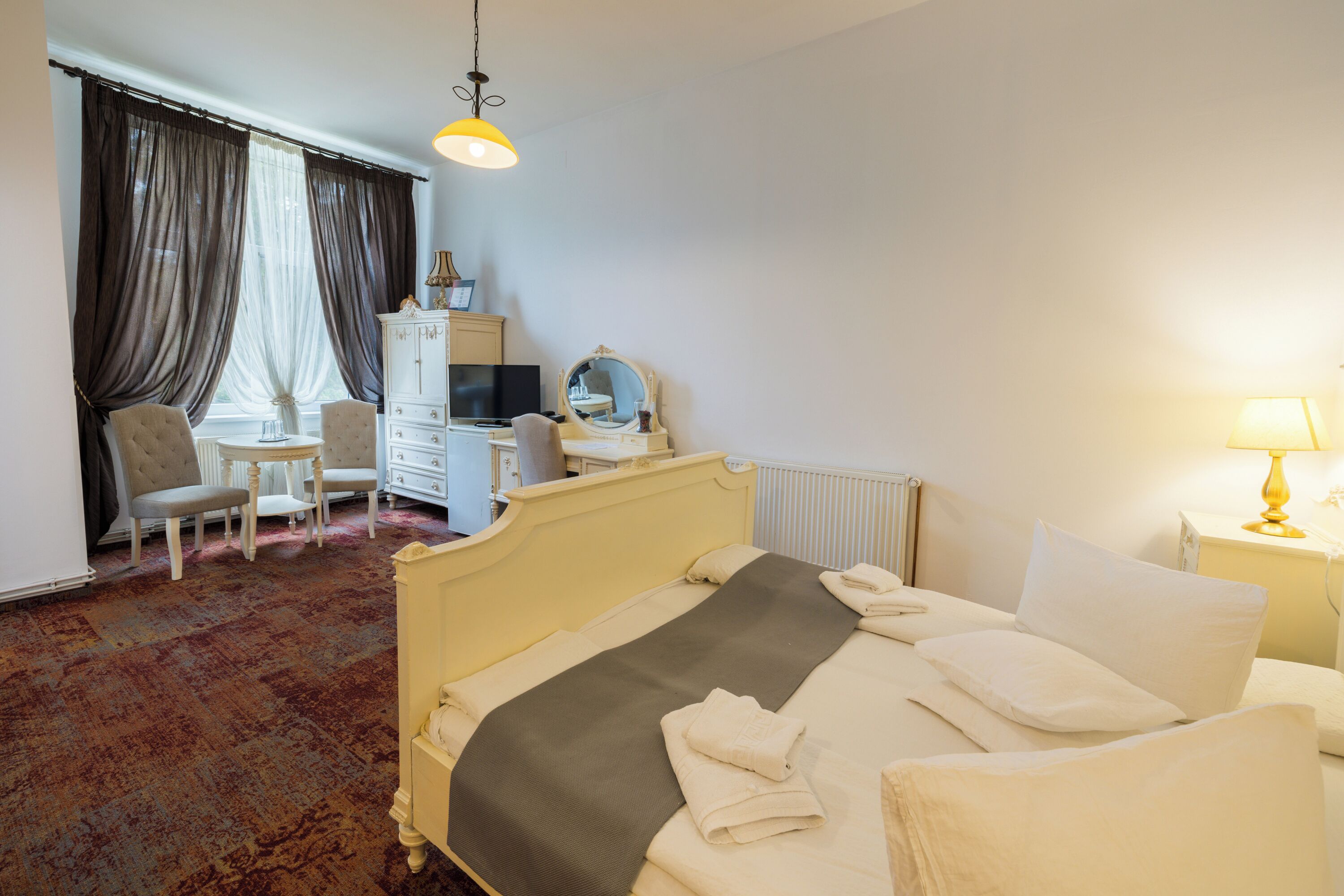 Habitació d'hotel amb llit, escriptori, cadira, commode i làmpada.