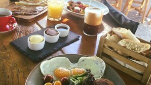A breakfast setting with a variety of dishes including eggs, bacon, sausages, toast, and beverages. - Marika's Aparts & Studios (Rhodes)