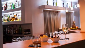 A bar area with shelves of liquor bottles, a bowl of snacks, and glasses of wine. - Marika's Aparts & Studios (Rhodes)