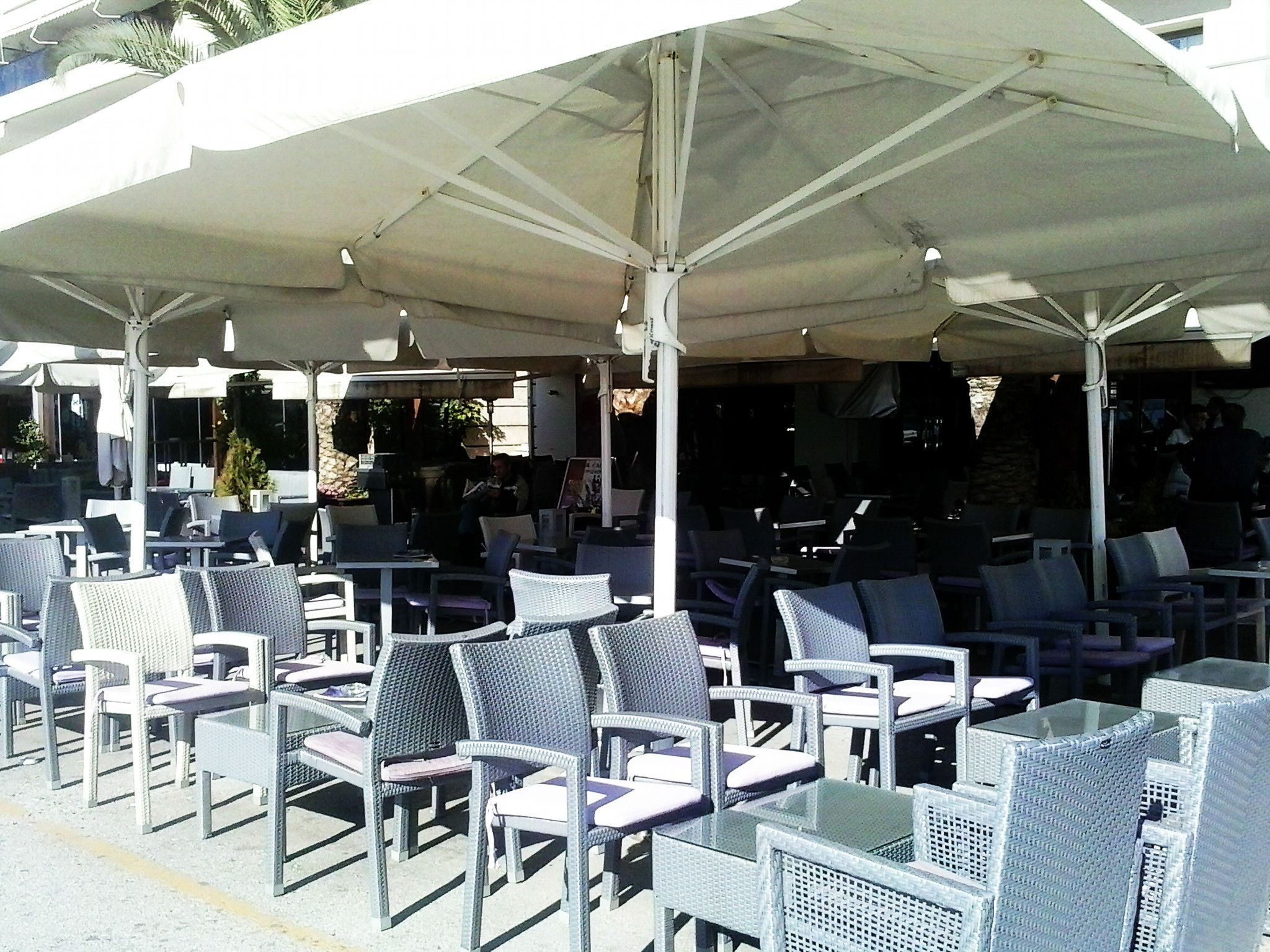An outdoor seating area with wicker chairs and tables under large umbrellas.