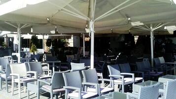 An outdoor seating area with wicker chairs and tables under large umbrellas.