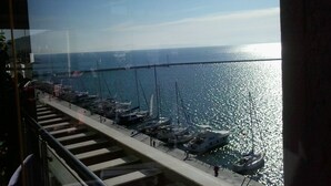 A marina with boats docked, a bridge in the background, and a clear sky. - Kipseli Hotel (Volos)