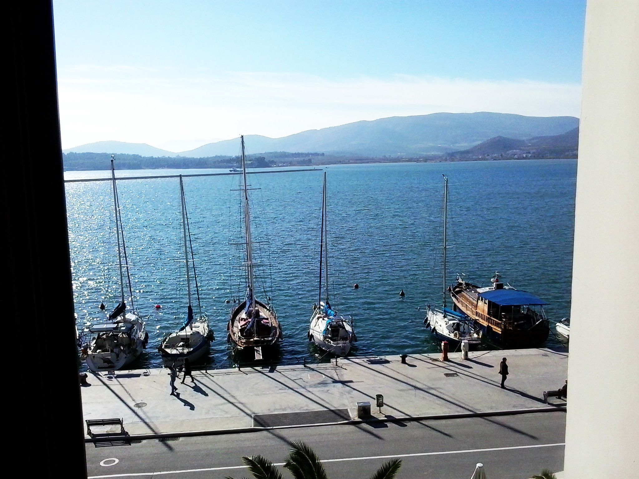 A marina with several boats docked, a pier, and a mountainous backdrop.