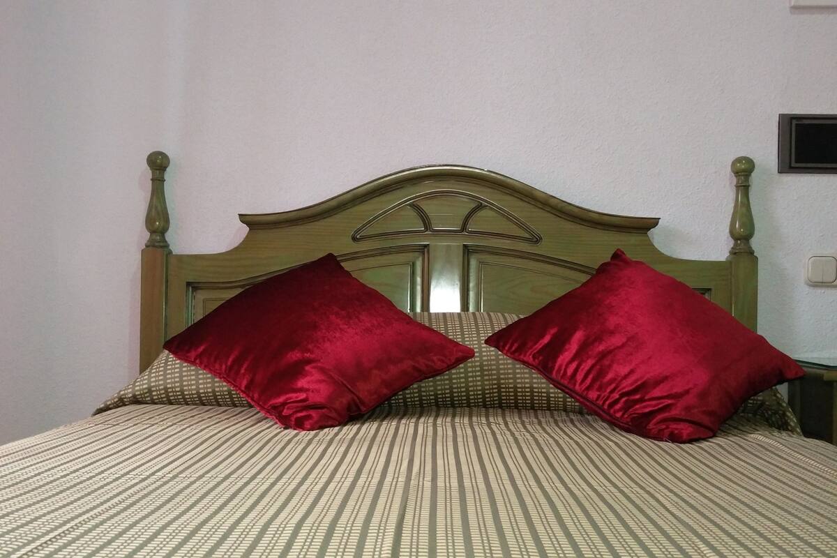 Una cama con cabecera de madera y dos almohadas rojas.