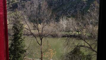 Vista de una colina con un edificio en la cima, una masa de agua y árboles en primer plano.