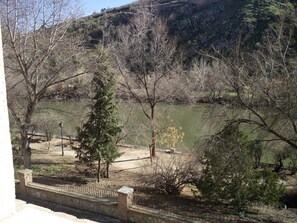 A view of a river with trees and a stone wall in the foreground. - Hotel El Diamantista (Toledo)