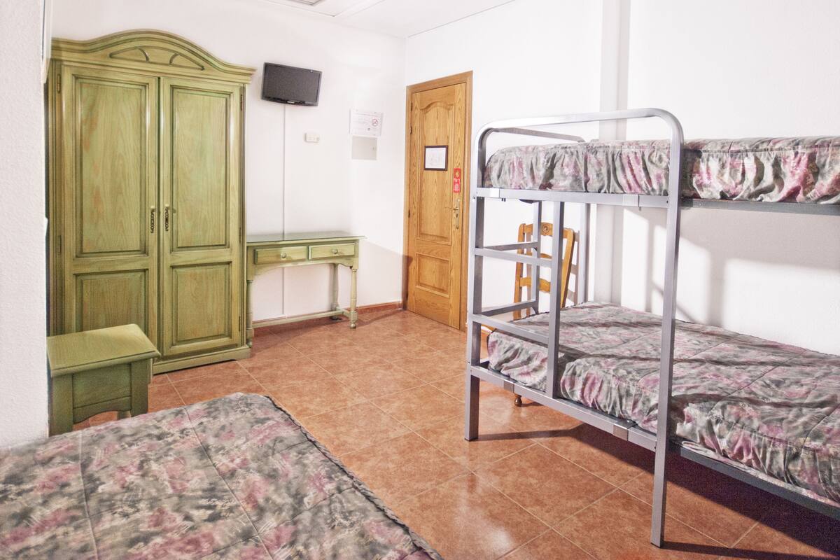 Un dormitorio con literas, un escritorio y un armario.