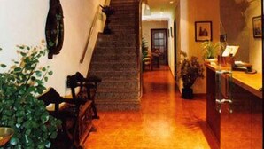 A staircase leading to a second floor, a reception desk, and a plant on the left. - Hotel El Diamantista (Toledo)