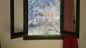 A room with a large window, a chair, and a red curtain. - Hotel El Diamantista (Toledo)