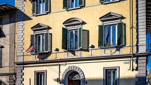 A multi-story building with a yellow facade, green shutters, and a central entrance with an archway. - Hotel Ferrucci Firenze (Florence)