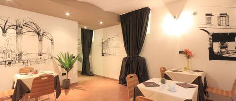 A dining area with tables and chairs, a plant, and wall art.