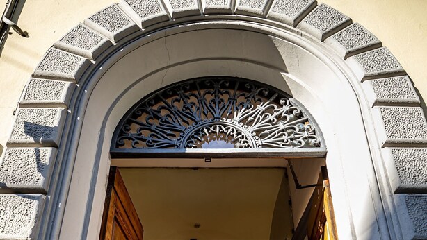 An entrance with a wooden door, glass doors, and a fire extinguisher. - Hotel Ferrucci Firenze (Florence)