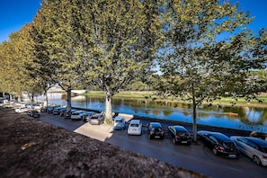 A parking area adjacent to a body of water with trees and a clear sky. - Hotel Ferrucci Firenze (Florence)