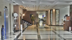 A hotel lobby with a modern design, featuring a large clock, a reception desk, and a potted plant. - KALI Escandon Mexico City (Mexico City)