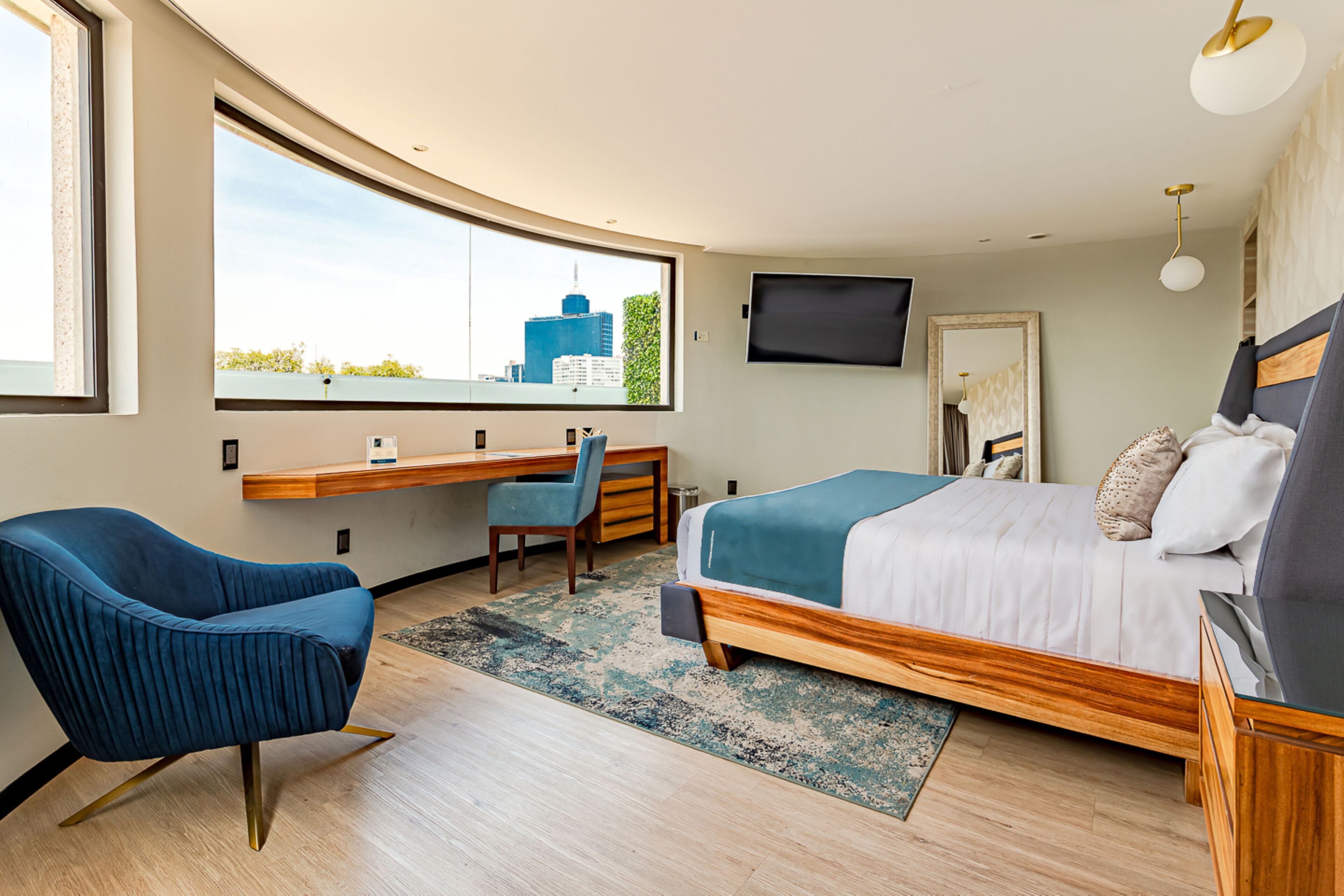 Une chambre à coucher moderne avec un lit, un bureau, une chaise et un téléviseur.