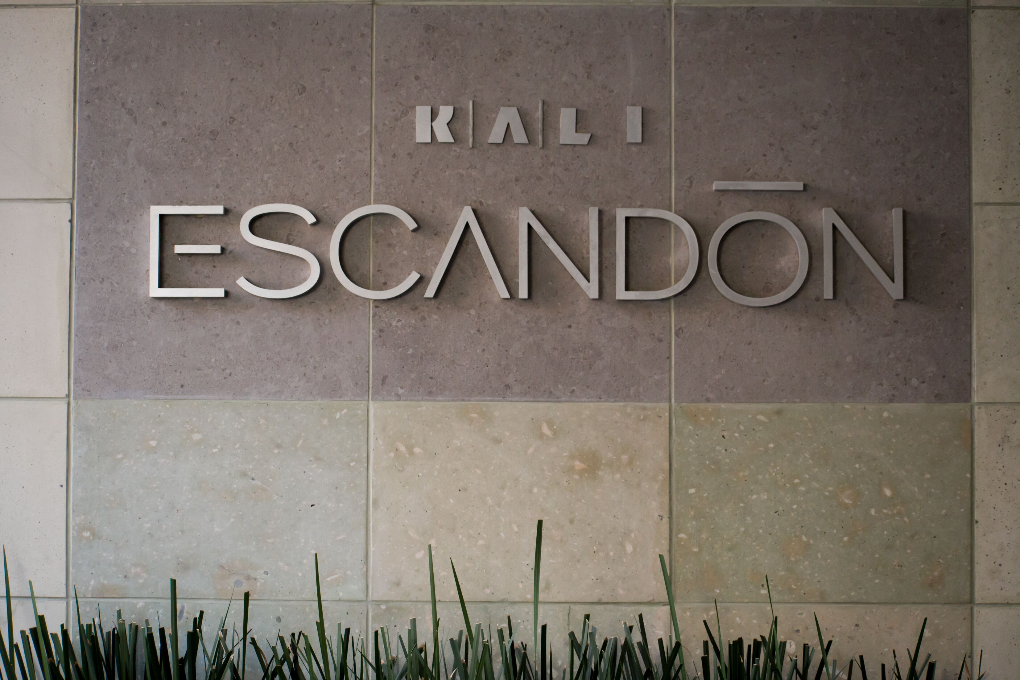 Un letrero con las palabras 'KALI ESCANDON' sobre una pared con azulejos.