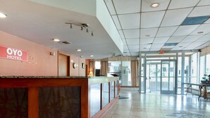 A hotel reception area with a reception desk, a clock, and an exit sign.