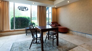 A modern room with a large window, a dining table with chairs, and a red sofa.