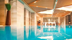 Una piscina interior moderna con techo de madera y un jarrón grande con plantas verdes.