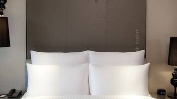 Een hotelkamer met een groot bed, een nachtkastje met een lamp, een telefoon en een digitale klok.