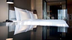 Habitación de hotel moderna con una cama grande, un teléfono en la mesita de noche y un separador de vidrio.