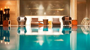 Un área de piscina interior moderna con sillones de descanso y velas.