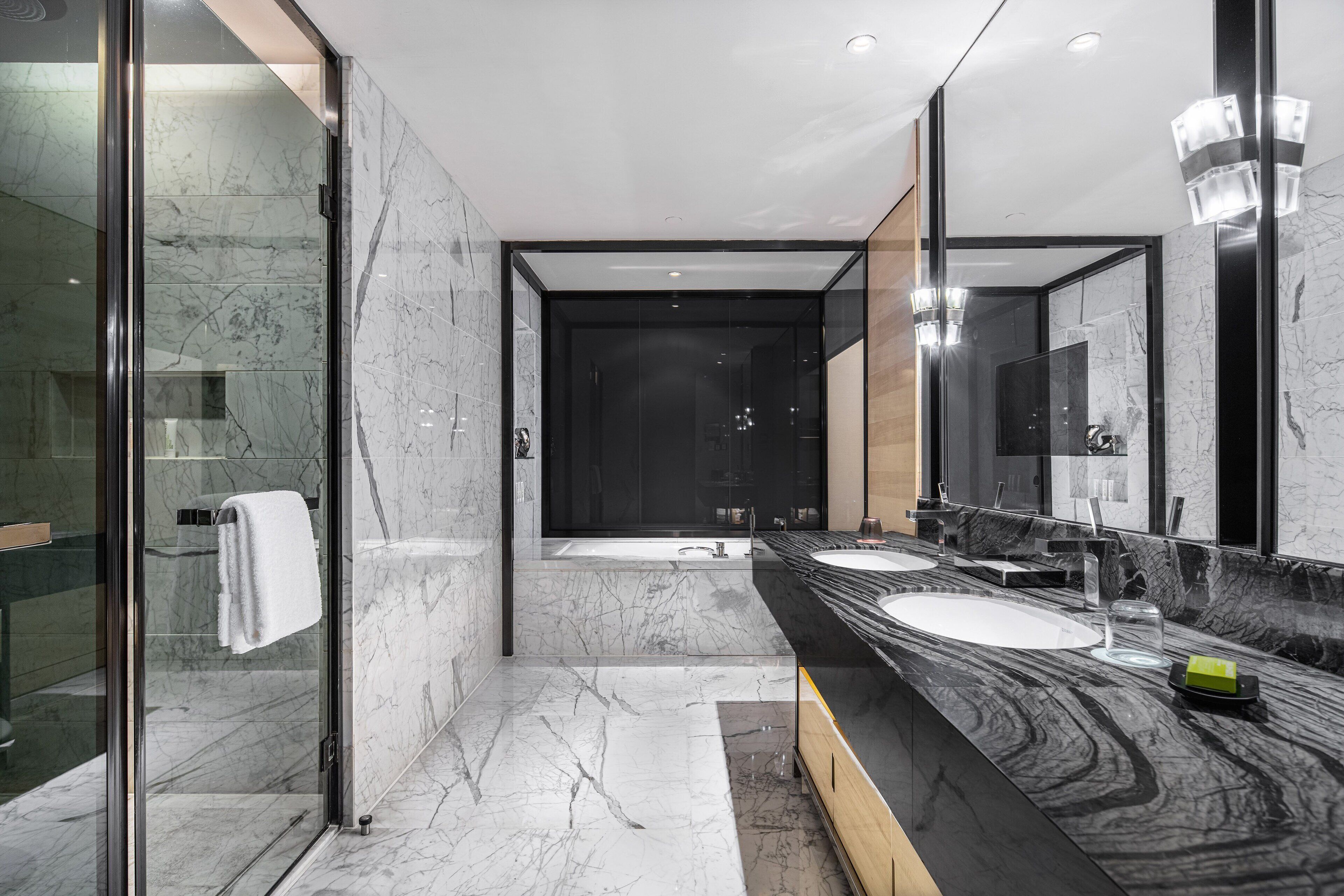A modern bathroom with a glass shower enclosure, two sinks, and a large mirror.