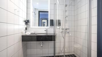 A modern bathroom with white tiles, a black countertop, a glass-enclosed shower, and a mirror with a lighted frame.