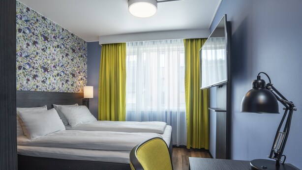 A hotel room with a bed, a desk with a lamp, and a chair. - Thon Hotel Tromsø (Tromsø)