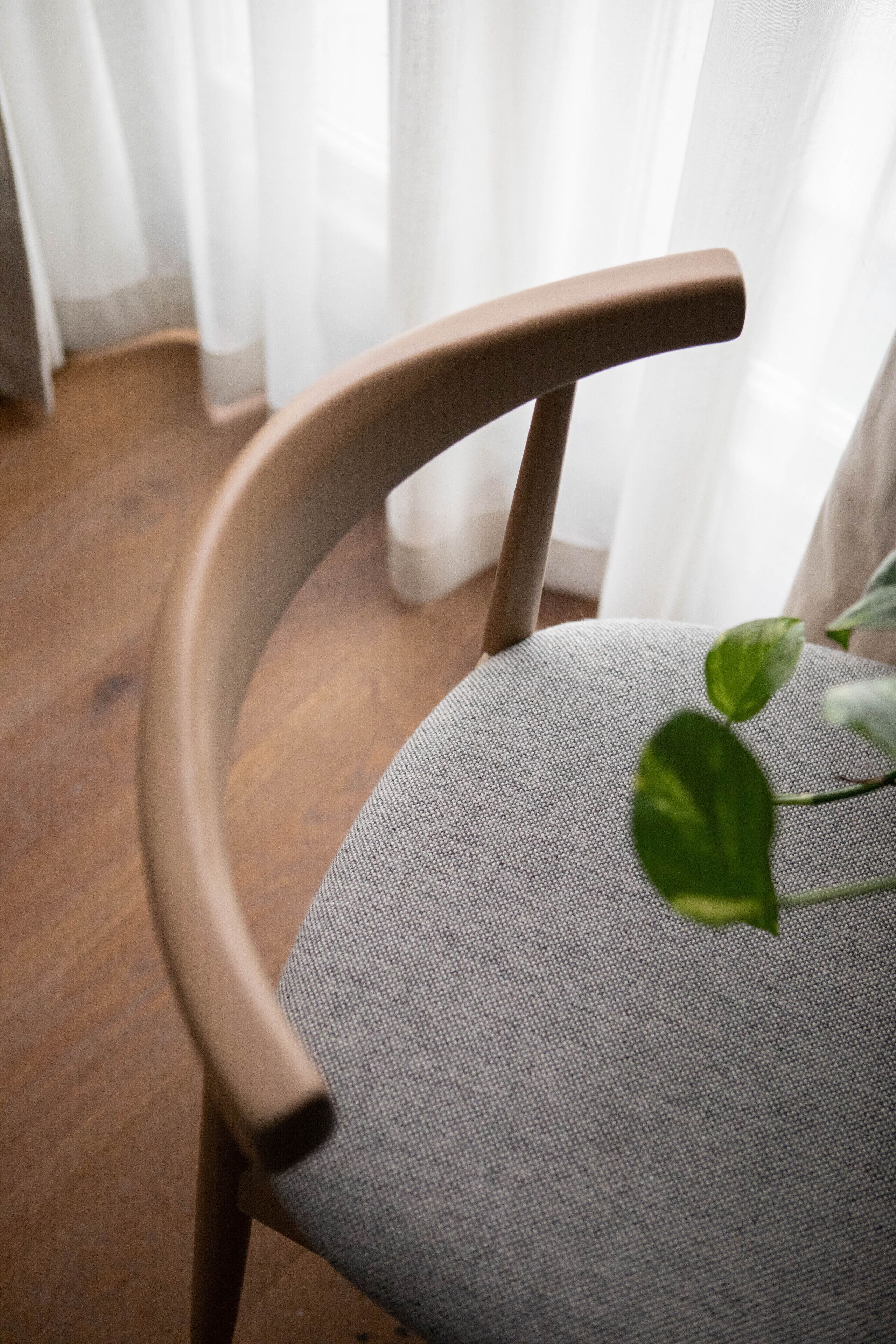 En stol med ett böjt ryggstöd och en grå tygklädd sits.