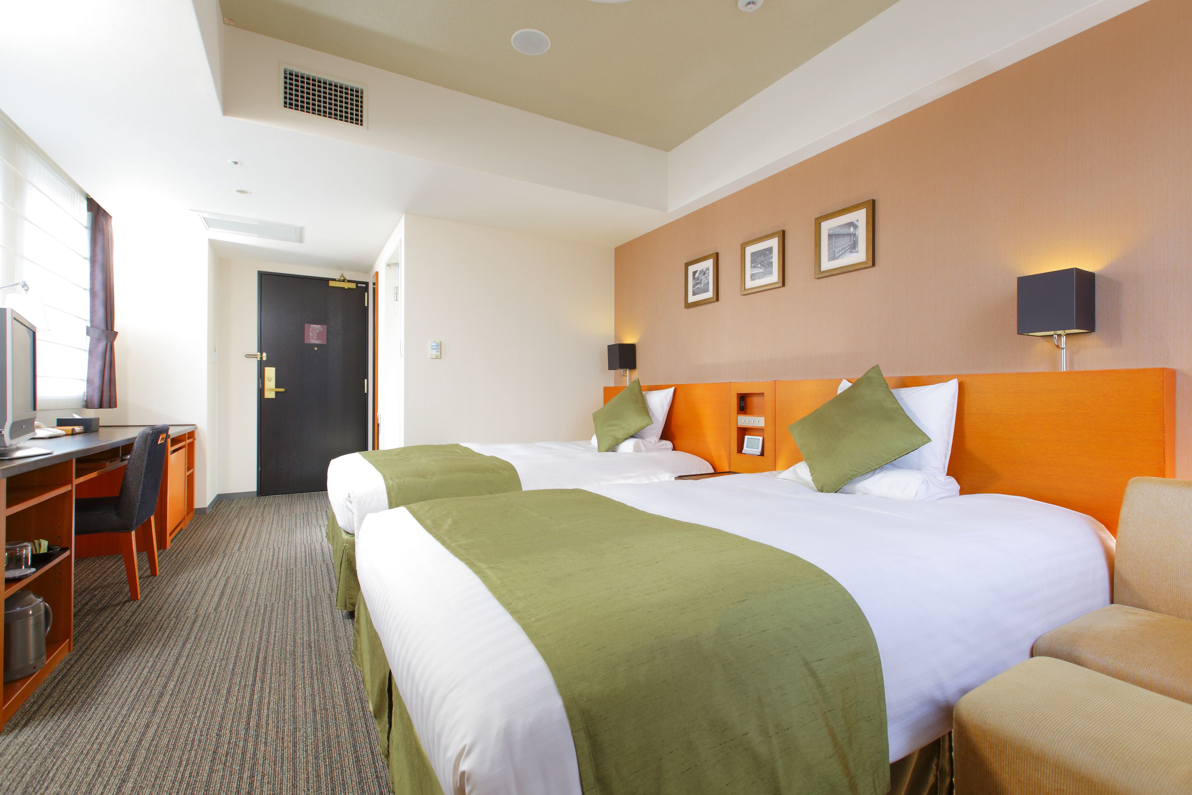 A hotel room with two beds, a desk, and a chair.
