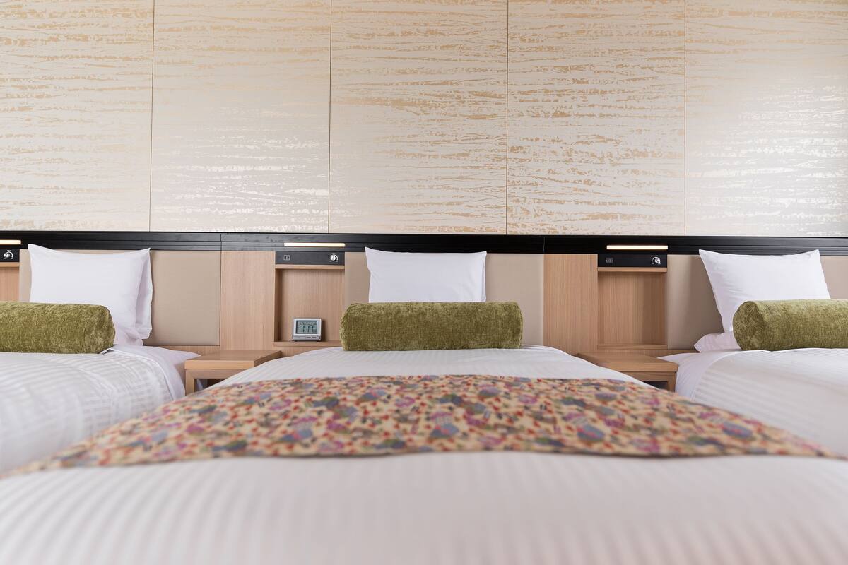 A hotel room with a large bed, two bedside tables, and a nightstand with a clock.