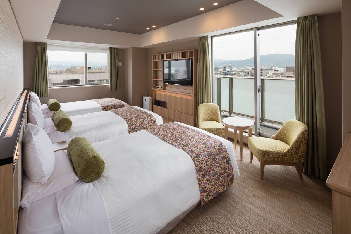 A hotel room with two beds, a TV, a small table, and a chair.
