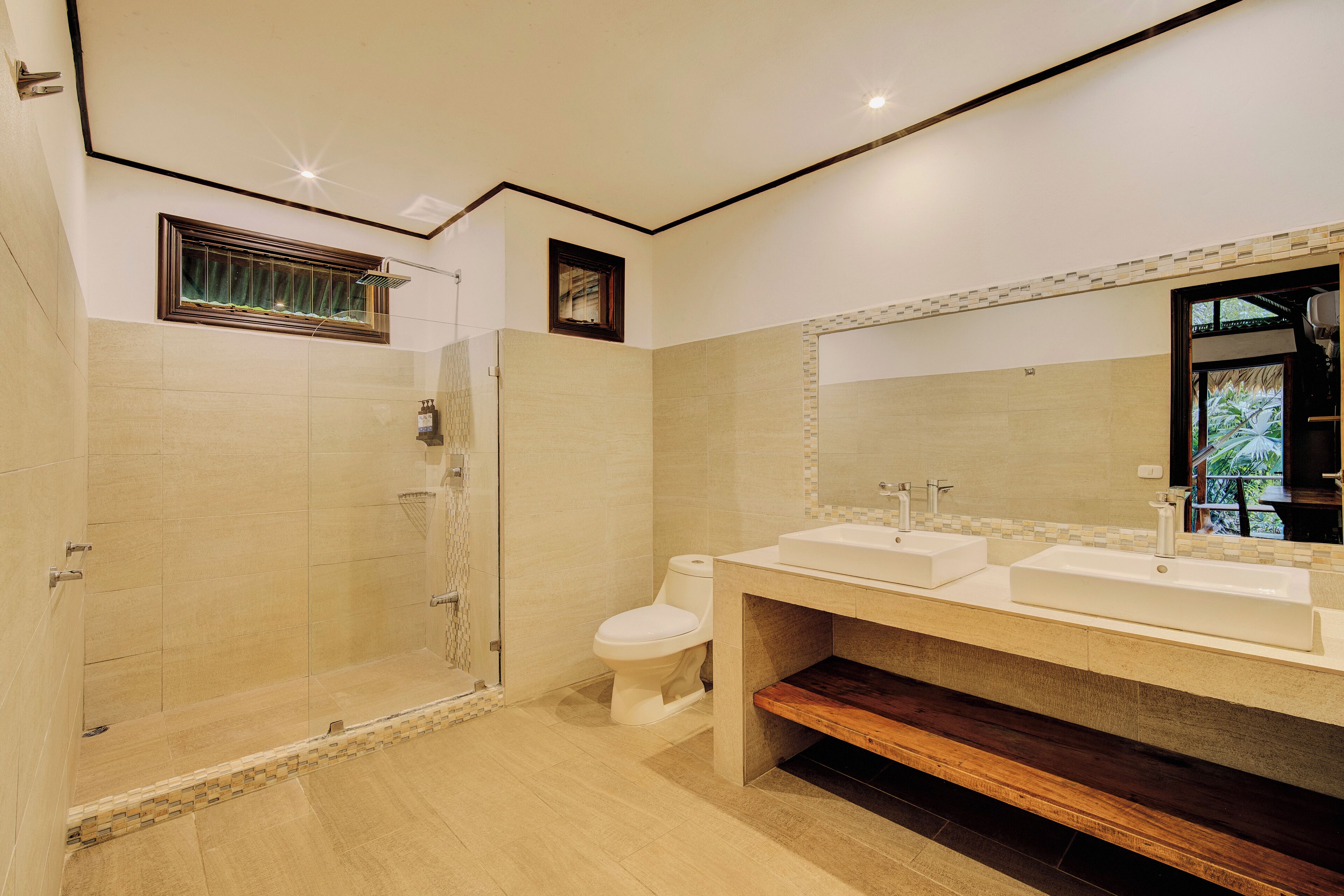 Ein modernes Badezimmer mit barrierefreier Dusche, Toilette und einem Waschtisch mit zwei Becken.