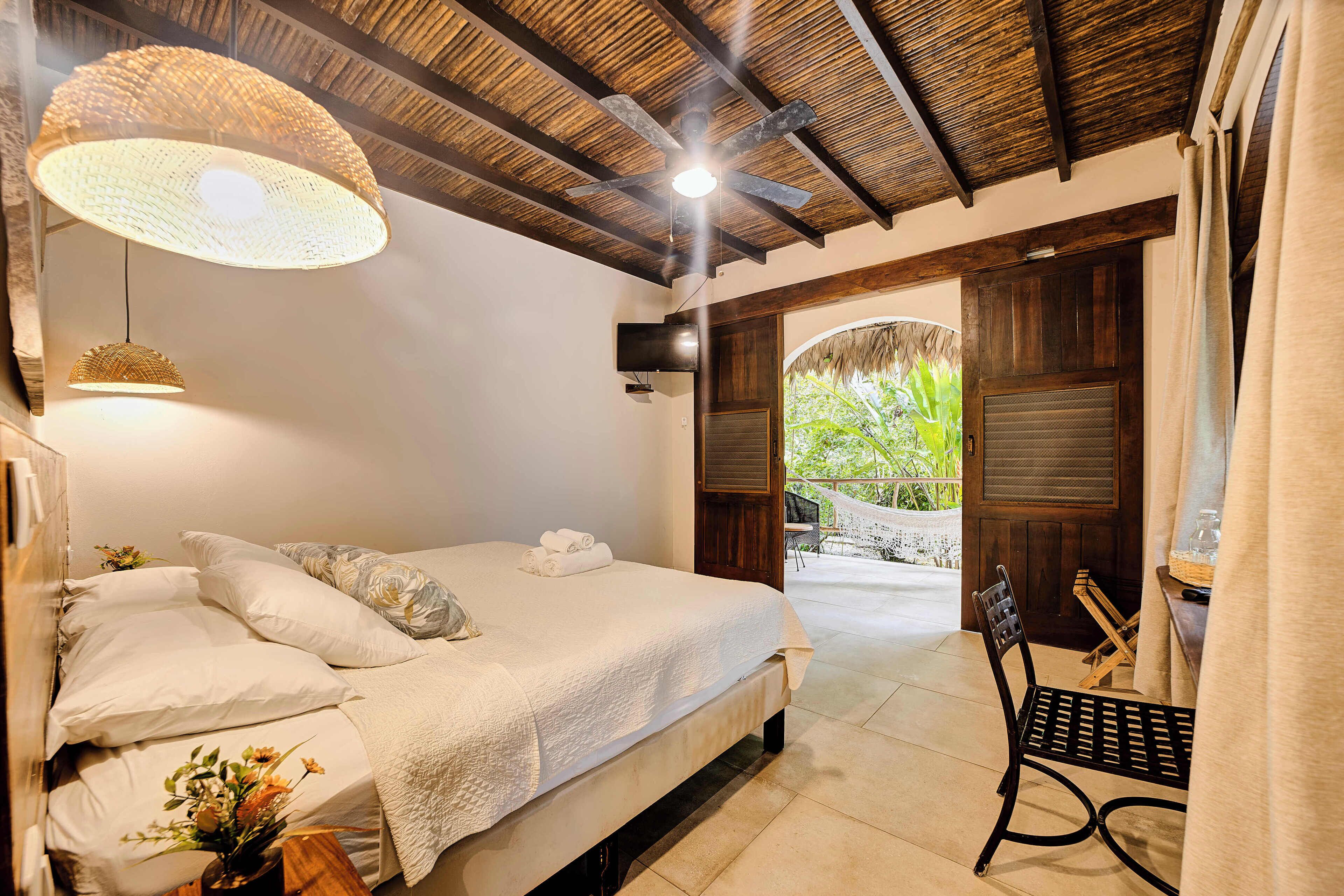 A bedroom with a bed, bedside table, and a view of a garden.