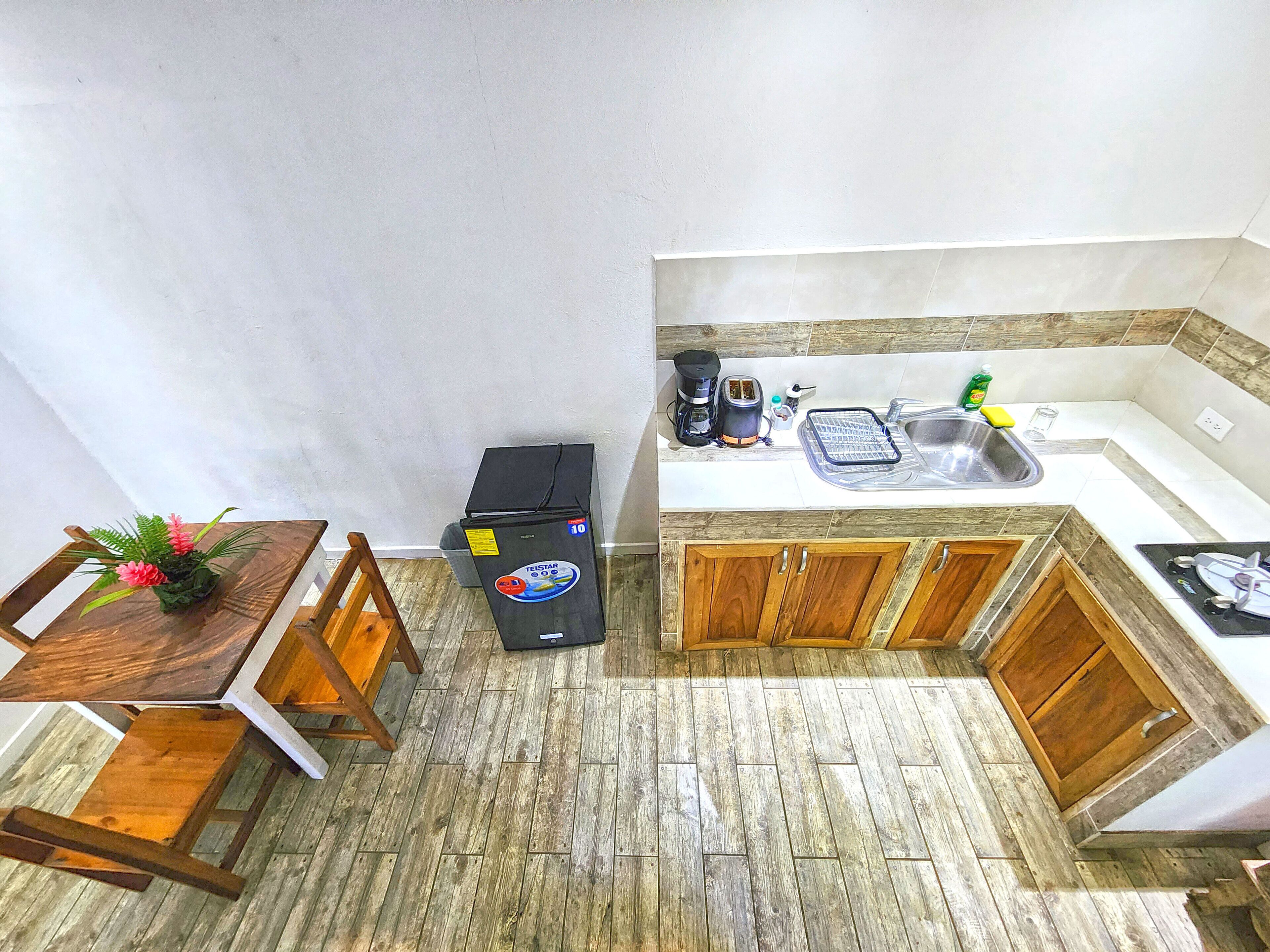 A compact kitchen with a sink, toaster, and wooden cabinets.