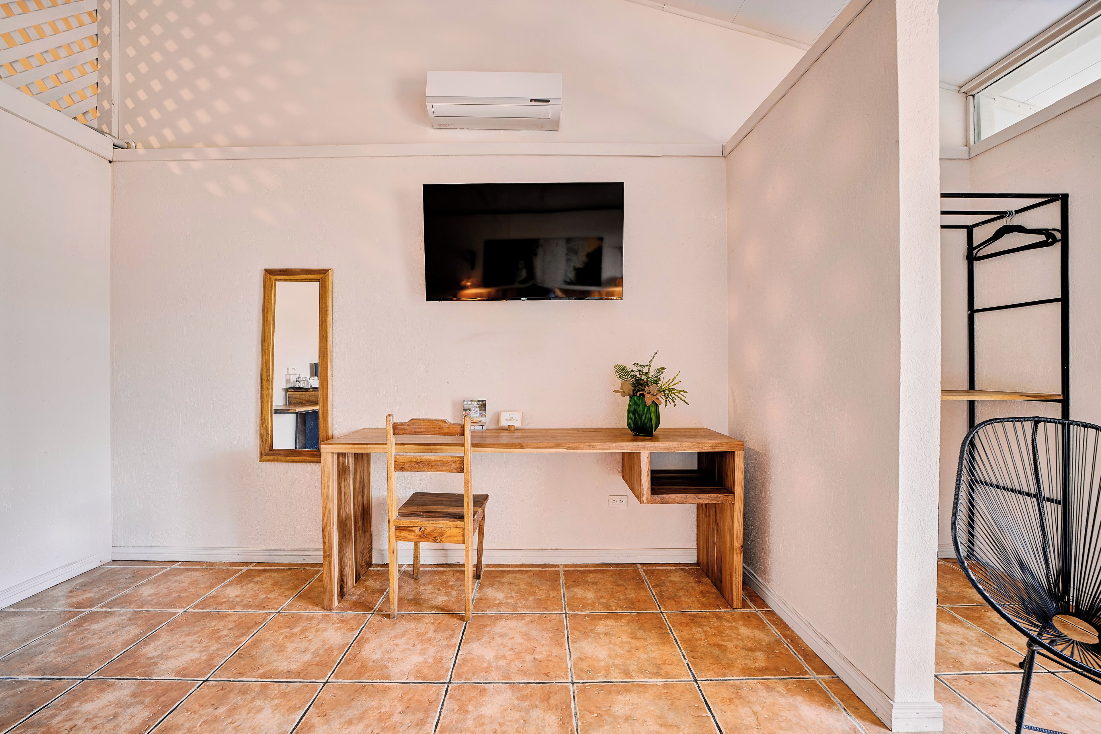 Une pièce avec un bureau en bois, une chaise et un téléviseur fixé au mur.