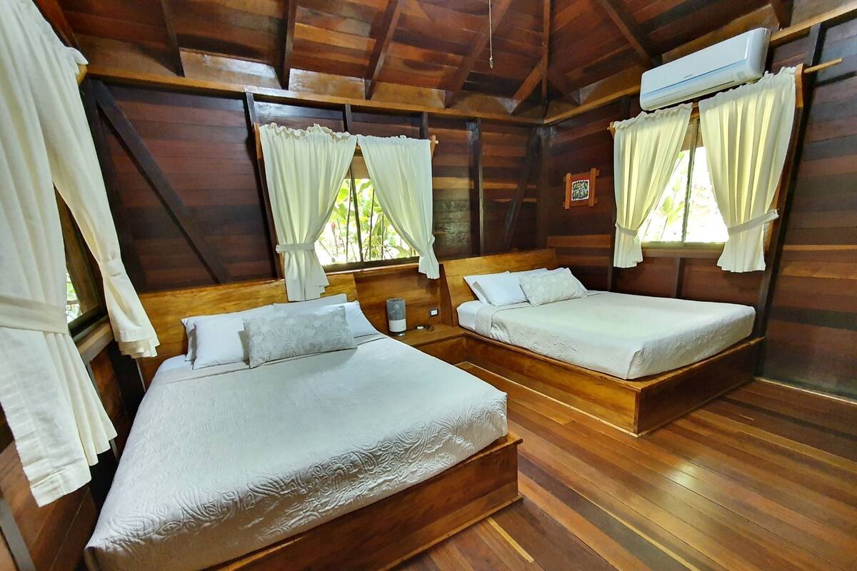 A room with two wooden beds, white bedding, and a ceiling fan.