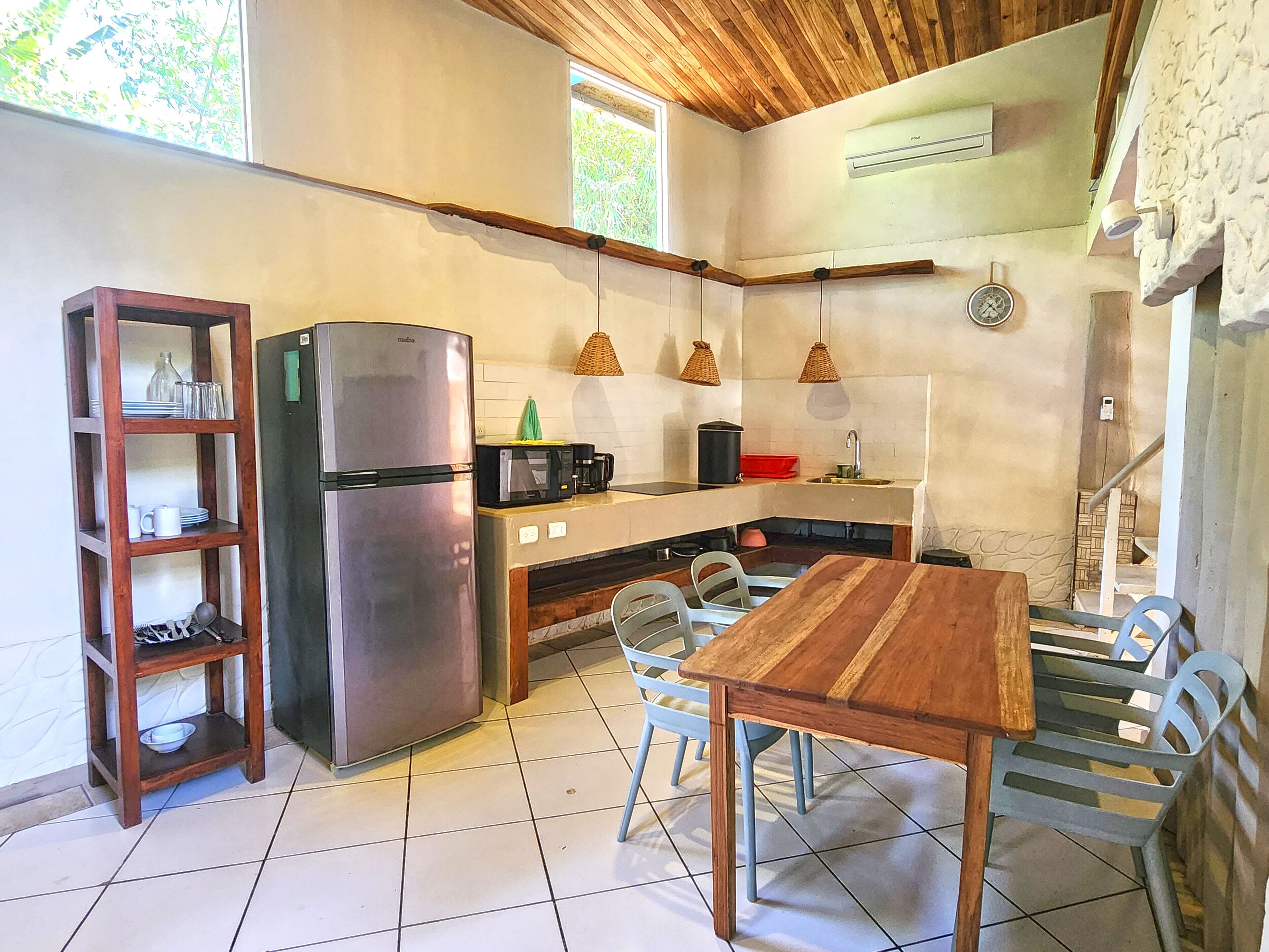 Une cuisine compacte équipée d’un réfrigérateur, d’un four à micro-ondes et d’une table à manger en bois.