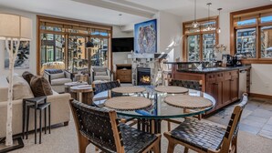 Een moderne keuken met een centraal eiland, een eetgedeelte met een glazen tafel, en een gezellige woonkamer met een open haard.