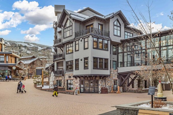 A multi-story building with a stone facade, large windows, and a balcony.