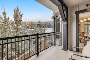 En balkon med udsigt over sneklædte træer og bygninger.