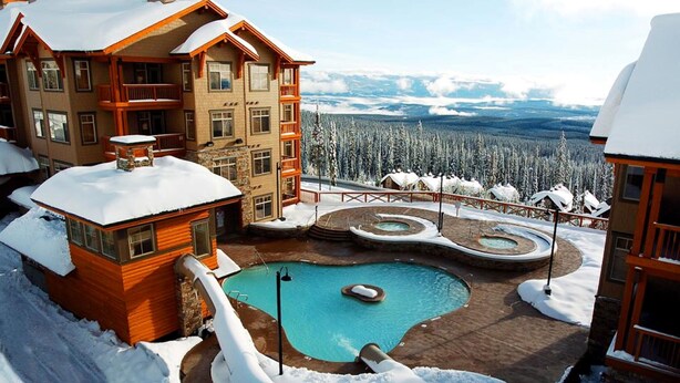A resort with a pool, wooden cabins, and a snowy landscape. - Sundance Resort (Beaverdell)