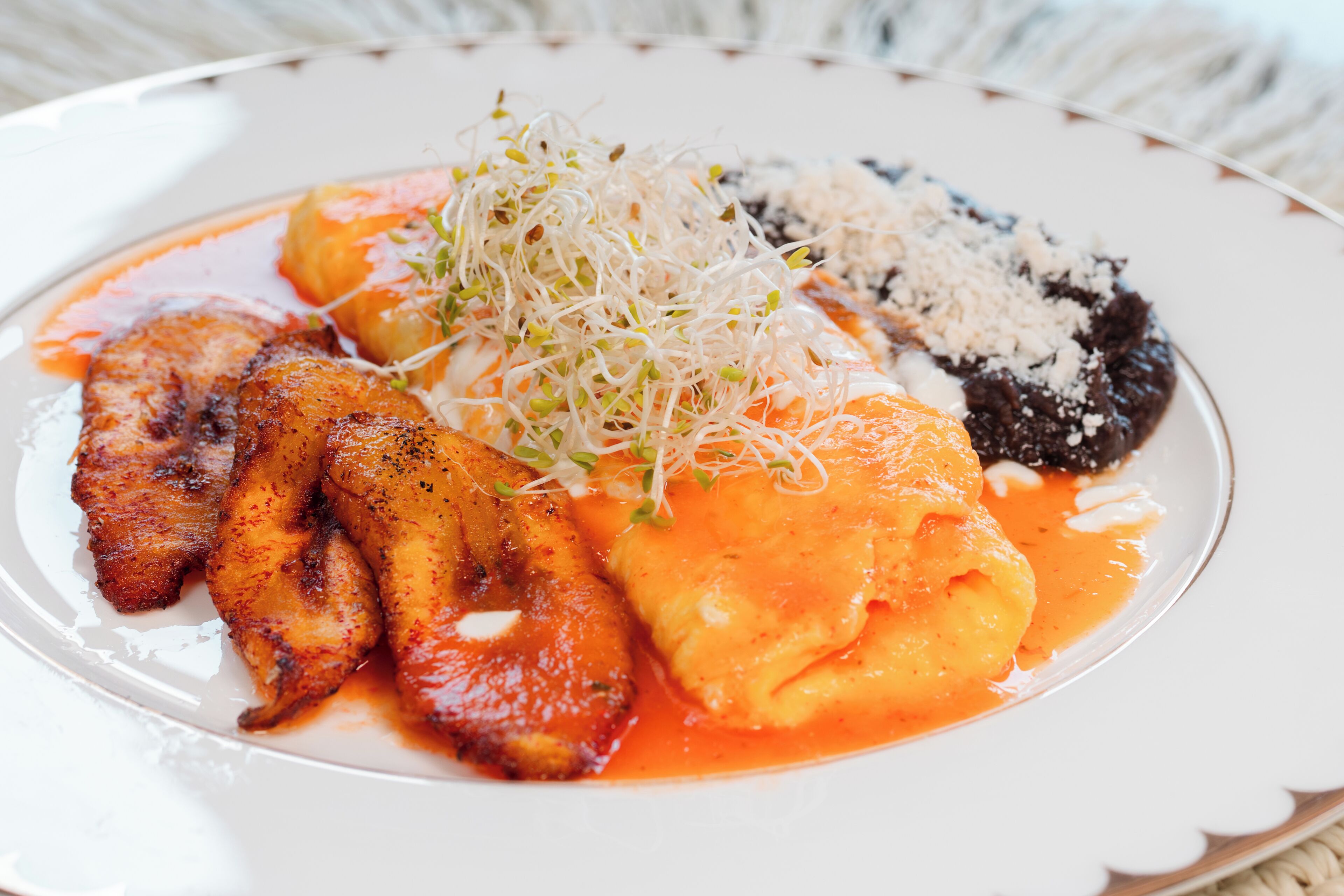 Un plato de comida con diferentes elementos, incluyendo carne a la parrilla, una fruta y algunos brotes.