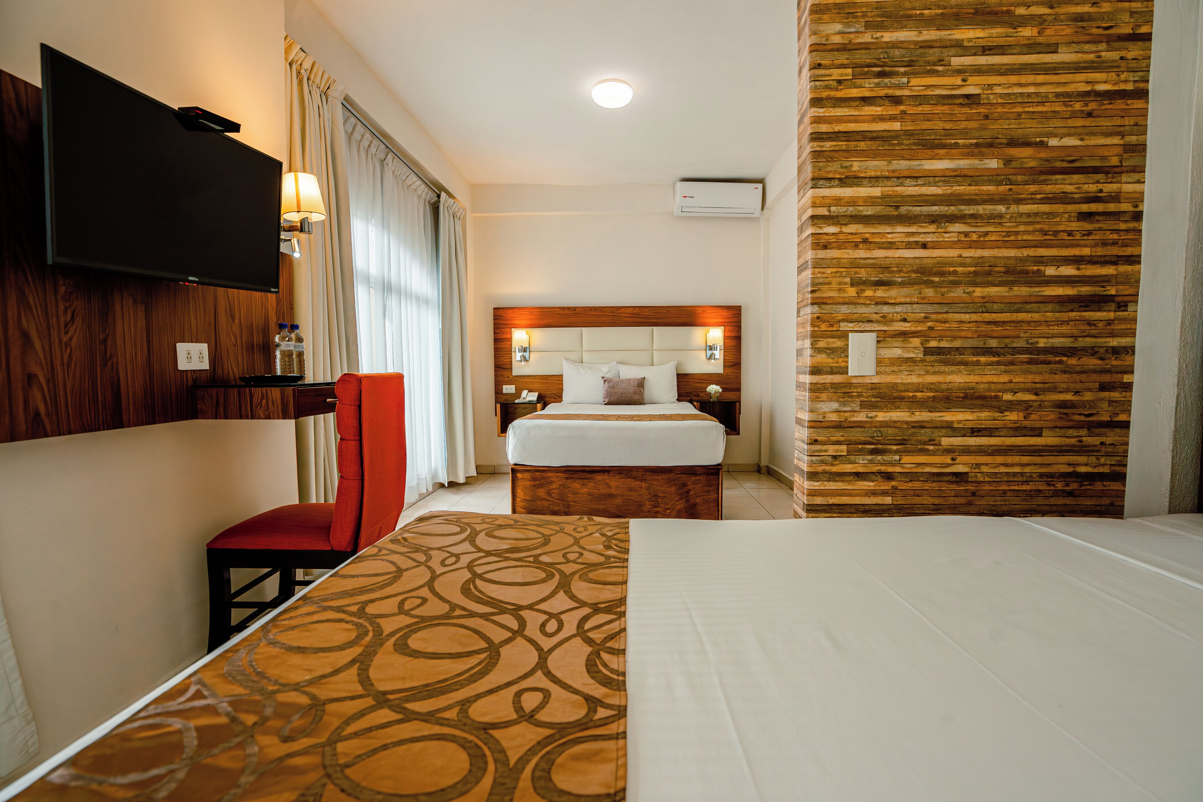 Una habitación de hotel con cama, televisión, escritorio y silla.
