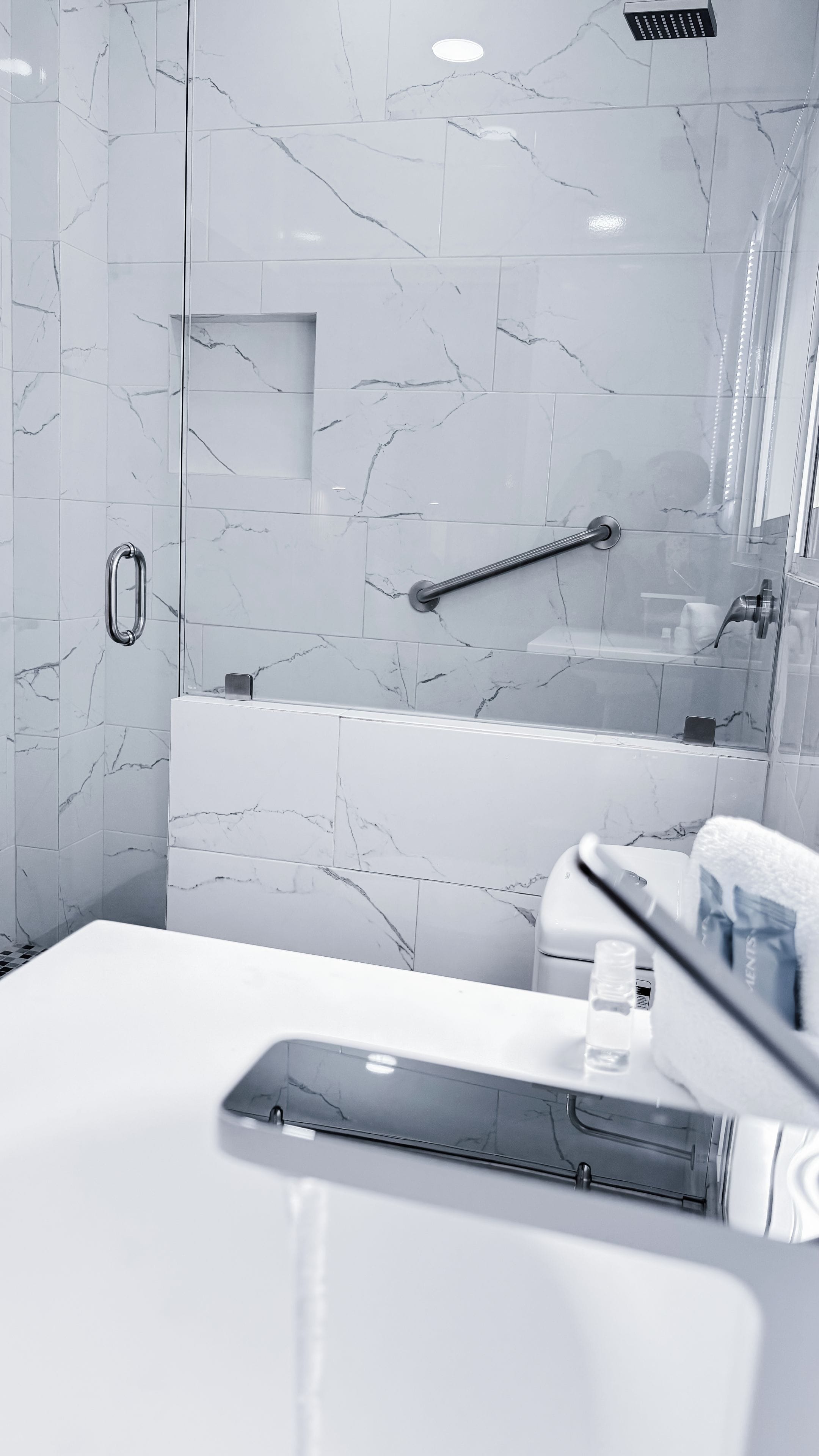 A modern bathroom with a marble backsplash, a bathtub, and a shower area.