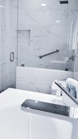 Un baño moderno con salpicadero de mármol, una bañera y zona de ducha.
