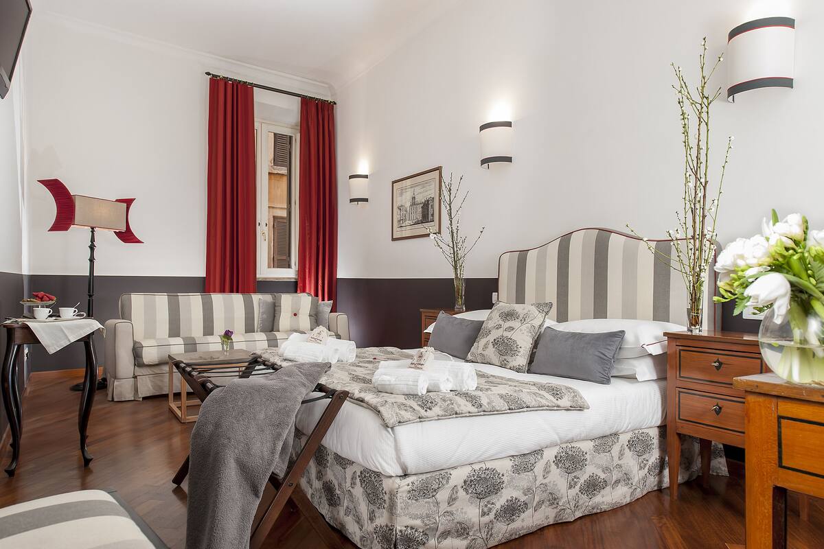 Habitación de hotel ordenada con cama, sofá, escritorio y silla.