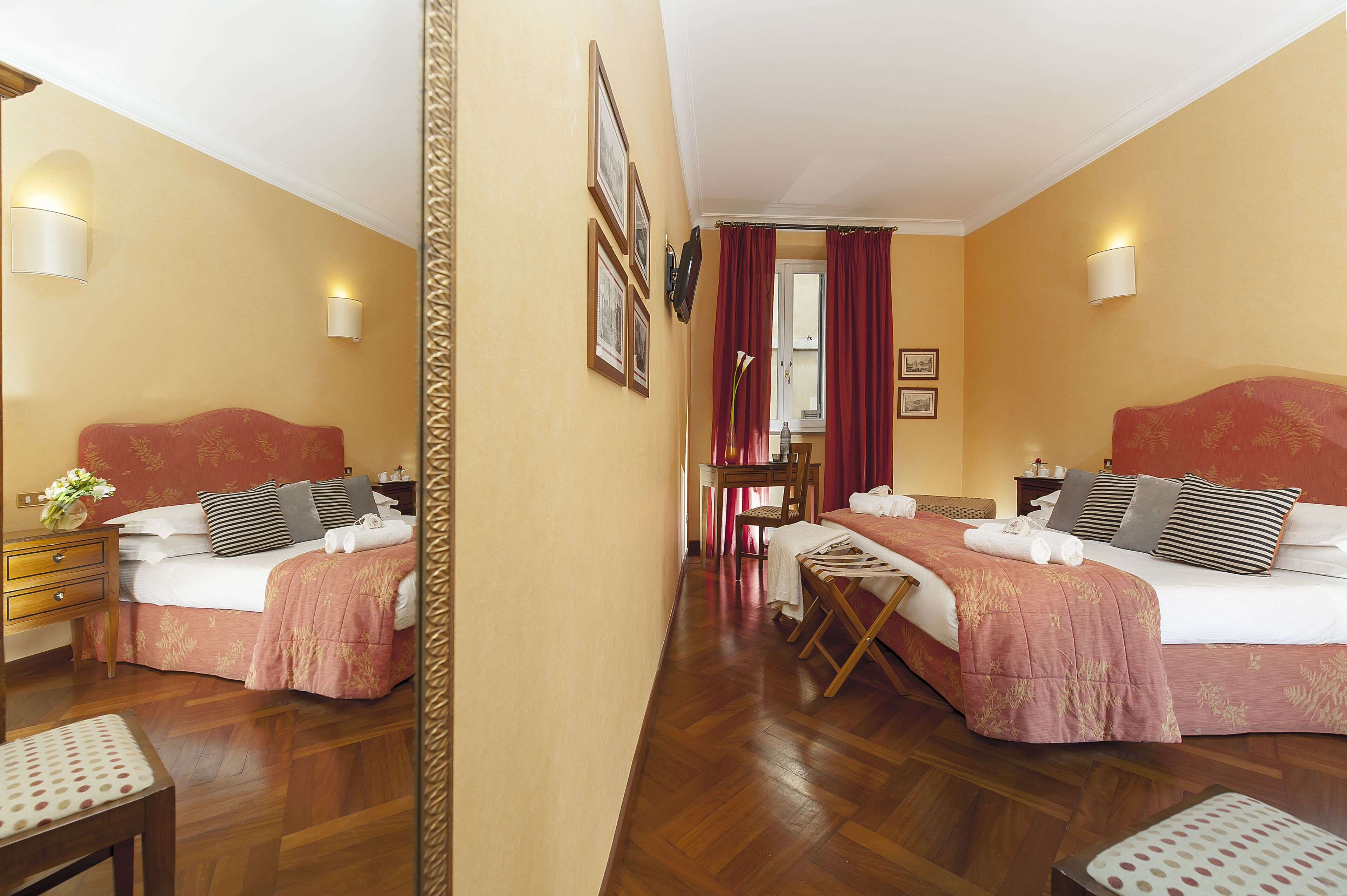 Habitación de hotel con dos camas, pisos de madera y un espejo.