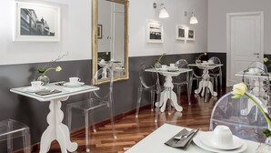 Ein moderner Essbereich mit klaren Glastischen und -stühlen, heller Dekoration und gerahmten Bildern an der Wand.
